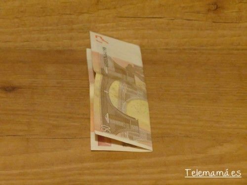 Comenzamos doblando el billete por la mitad.